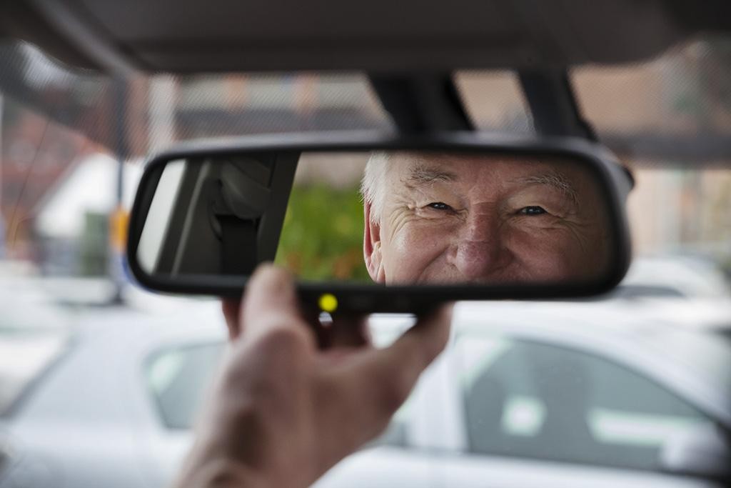 Kuvassa iäkäs henkilö auton ratissa