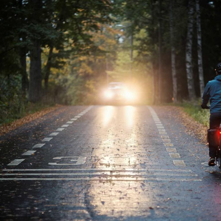 Kuvassa pyöräilijä ajaa pimeällä valot päällä.