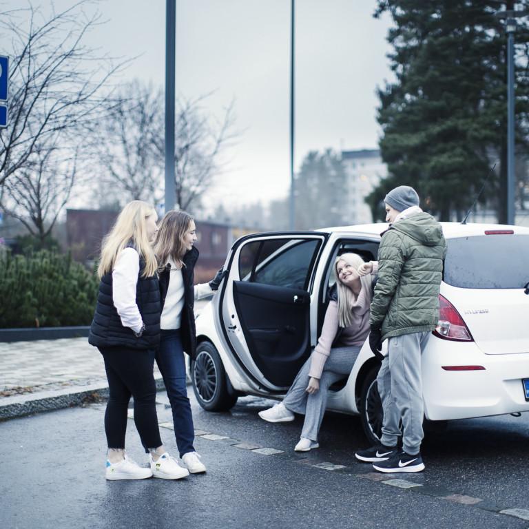 Kuvassa neljä nuorta ihmistä juttelee auton luona.